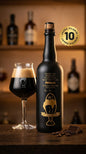 Mattschwarze 75 cl Flasche Jubiläumsbier 2025 Blackfish mit goldener Beschriftung neben gefülltem Bierglas auf Holztisch.