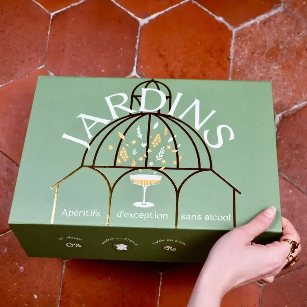 Grüne Geschenkbox „Jardins Fleuris“ mit goldener Kuppel-Illustration und weißem Schriftzug auf rotem Fliesenboden.