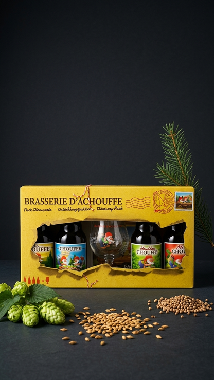 Gelbes LA CHOUFFE Geschenkkarton mit Bierflaschen, Bierglas und dekorativen Hopfen- und Gerstenkörnern.